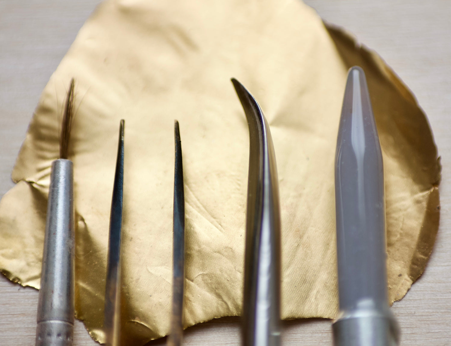 Jewellery tools and tweezers lying on top of a thin sheet of 24ct gold