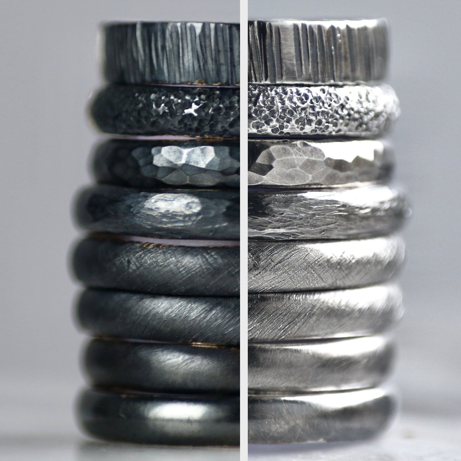 Stack of oxidised silver rings with textured surfaces on a grey background